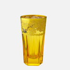 A translucent yellow glass tumbler with a faceted, ribbed design and a frosted pattern near the top, shown on a solid light gray background.